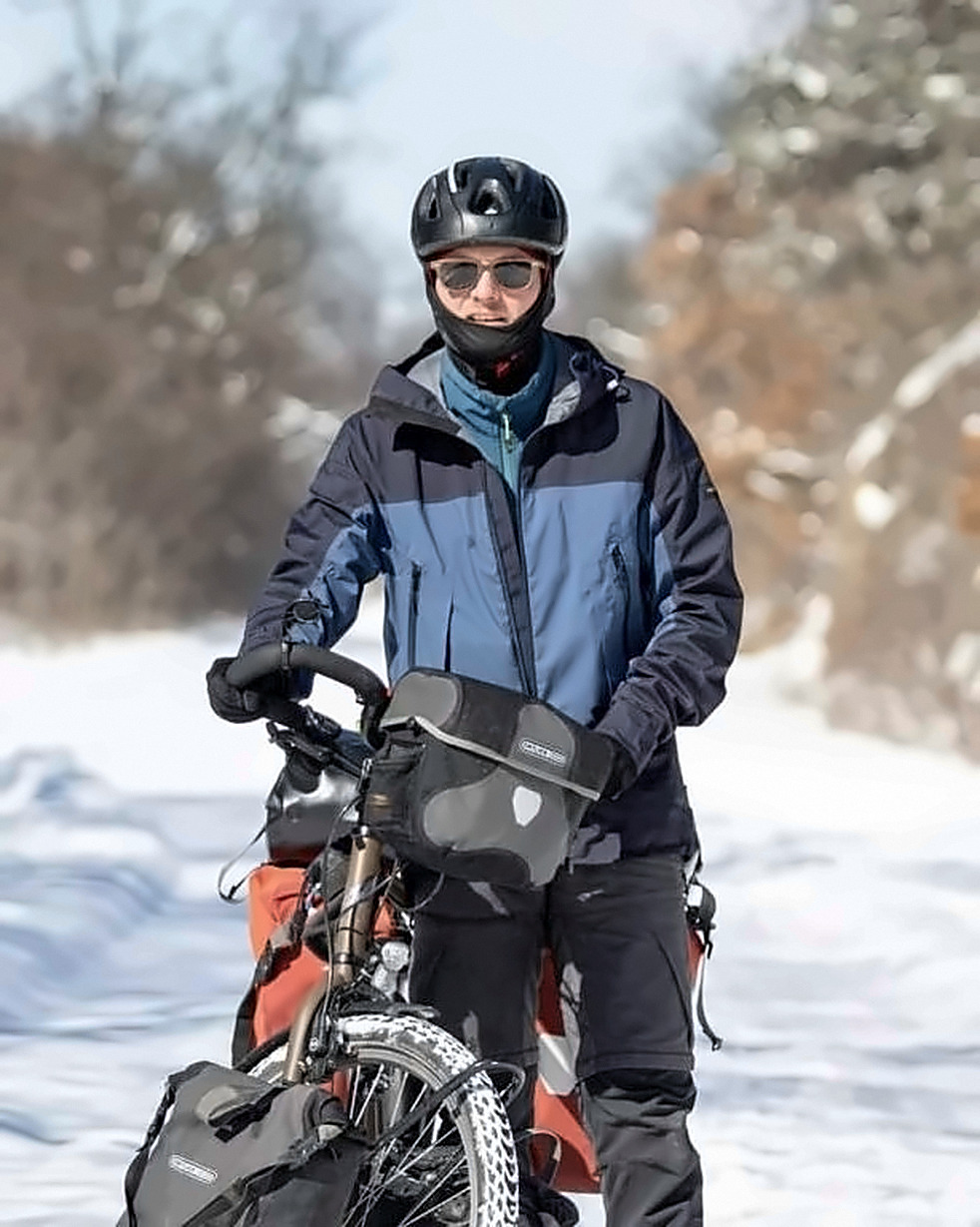 Bastien avec son vélo de voyage sur une route enneigée